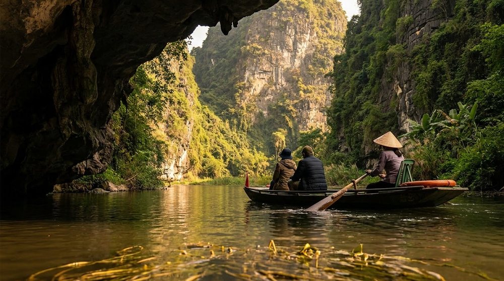 A rowing boat leaving a limestone cave on the river at Trang An